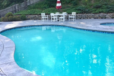 Mid-sized elegant backyard concrete paver and custom-shaped hot tub photo in Boston