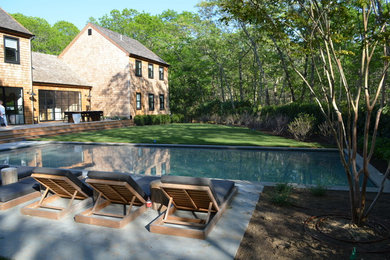 Foto de piscina alargada clásica renovada grande rectangular en patio trasero con adoquines de hormigón