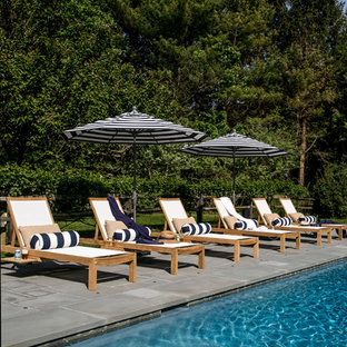 This is an example of an expansive beach style backyard custom-shaped natural pool in New York with natural stone pavers.
