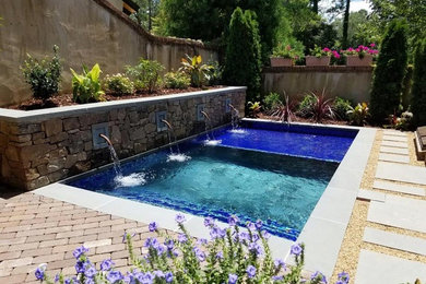 Modelo de piscina con fuente contemporánea de tamaño medio rectangular en patio trasero con adoquines de ladrillo