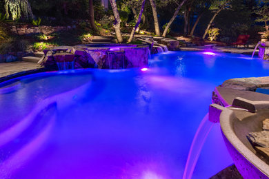 Hot tub - large mediterranean backyard stone and custom-shaped hot tub idea in Sacramento