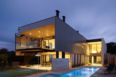 Diseño de casa de la piscina y piscina alargada costera grande rectangular en patio trasero con adoquines de piedra natural