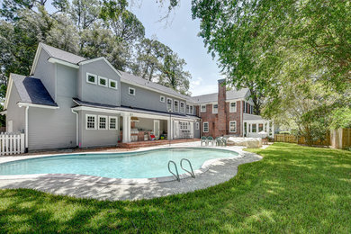 Photo of a large traditional back custom shaped swimming pool in Jacksonville with natural stone paving.