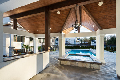 Imagen de casa de la piscina y piscina tradicional extra grande en patio trasero con losas de hormigón
