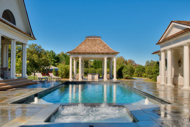 Example of a large classic backyard stone and round pool house design in Other