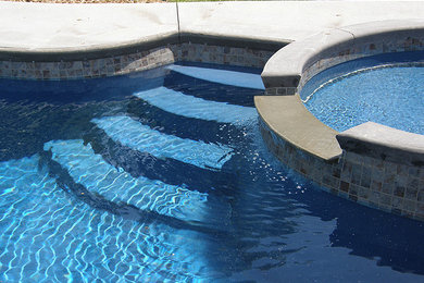 Diseño de piscina con fuente elevada a medida en patio trasero con losas de hormigón