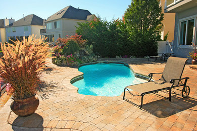 Ejemplo de piscina con fuente clásica renovada pequeña a medida en patio trasero con adoquines de ladrillo