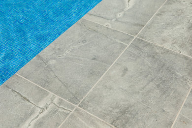 Ejemplo de piscina moderna grande rectangular en patio trasero con adoquines de piedra natural
