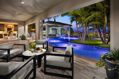 Diseño de casa de la piscina y piscina infinita tropical grande en forma de L en patio trasero con suelo de baldosas