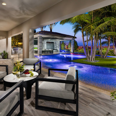 Example of a large island style backyard tile and l-shaped infinity pool house design in San Diego