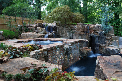 Hot tub - large rustic backyard stone and custom-shaped natural hot tub idea in Other