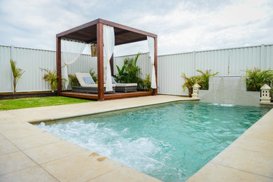 Imagen de piscina contemporánea de tamaño medio rectangular en patio trasero con adoquines de hormigón