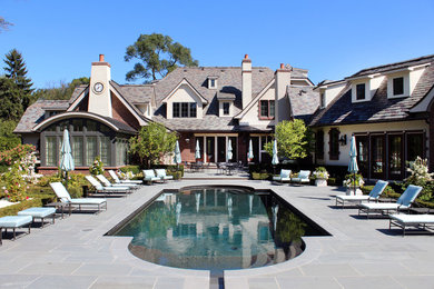 На фото: большой бассейн произвольной формы на заднем дворе в классическом стиле с покрытием из каменной брусчатки