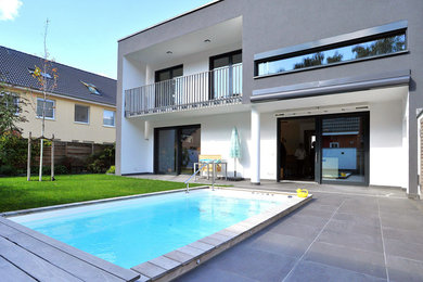 Diseño de piscina actual grande rectangular en patio trasero con entablado