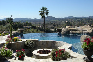 Foto de piscina con fuente infinita mediterránea grande tipo riñón en patio trasero con adoquines de hormigón