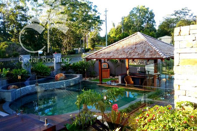 Foto de casa de la piscina y piscina natural tropical de tamaño medio a medida en patio delantero con entablado