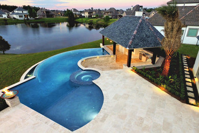 Large trendy backyard custom-shaped infinity pool house photo in New Orleans with decking