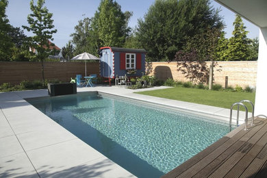 Modelo de casa de la piscina y piscina alargada contemporánea de tamaño medio rectangular en patio trasero con suelo de baldosas