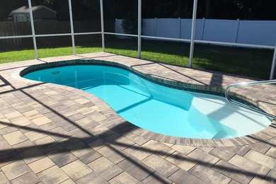 Pool house - mid-sized traditional backyard tile and kidney-shaped lap pool house idea in Orlando