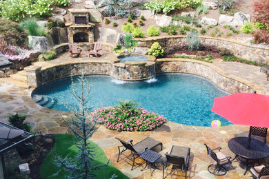 Example of an island style backyard kidney-shaped natural hot tub design in Atlanta