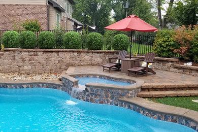 Large elegant backyard stamped concrete and custom-shaped pool photo in St Louis