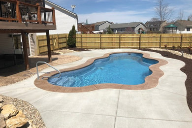 Example of a large classic backyard stamped concrete and custom-shaped pool design in St Louis