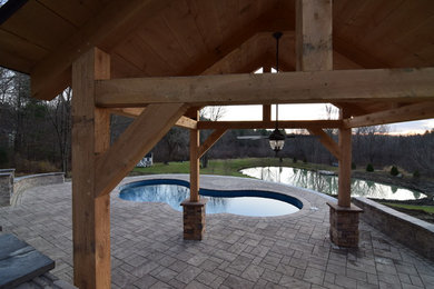 Diseño de piscina con tobogán grande a medida en patio trasero con adoquines de hormigón