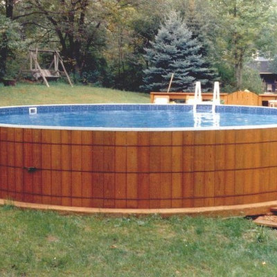 Example of a tuscan backyard concrete and round aboveground pool design in New York