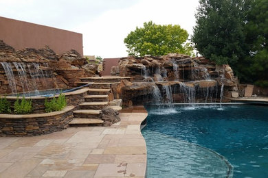 This is an example of a medium sized back custom shaped natural hot tub in Albuquerque with natural stone paving.