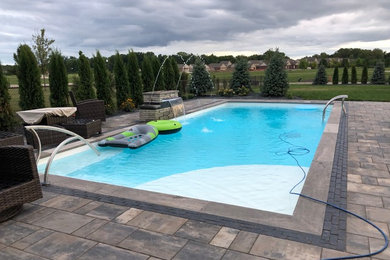 Pool fountain - large backyard brick and rectangular natural pool fountain idea in Detroit
