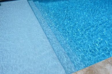 Diseño de piscina campestre de tamaño medio rectangular en patio trasero con losas de hormigón