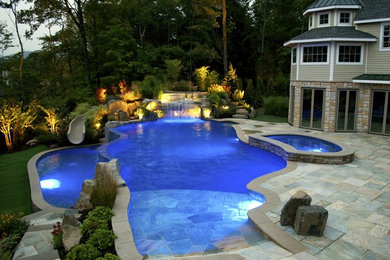 Water slide - mid-sized tropical backyard stone and custom-shaped infinity water slide idea in Orlando