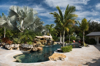 Inspiration for a mid-sized tropical backyard stone and custom-shaped pool fountain remodel in New York