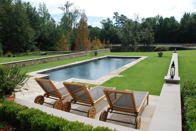 Diseño de piscina grande rectangular en patio trasero con adoquines de piedra natural