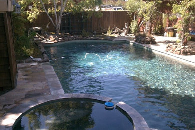 Example of a large backyard concrete paver and custom-shaped hot tub design in San Francisco