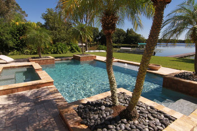 Diseño de piscina con fuente alargada mediterránea de tamaño medio rectangular en patio trasero con adoquines de piedra natural