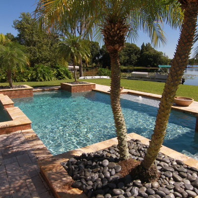 Example of a mid-sized tuscan backyard stone and rectangular lap pool fountain design in Tampa