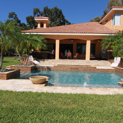 Example of a mid-sized tuscan backyard stone and rectangular lap pool fountain design in Tampa