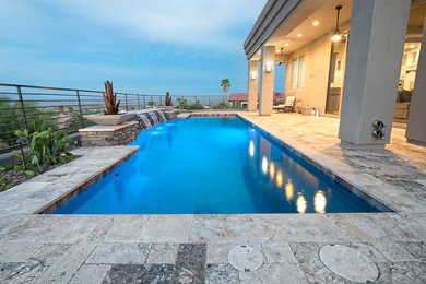 Imagen de piscina con fuente actual de tamaño medio rectangular en patio con adoquines de piedra natural