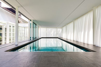 Moderner Indoor-Pool in rechteckiger Form mit Natursteinplatten in München