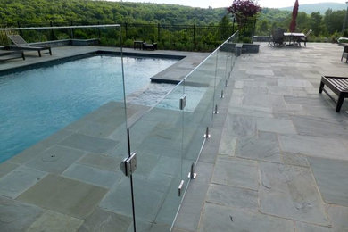На фото: естественный, прямоугольный бассейн среднего размера на заднем дворе в стиле модернизм с покрытием из плитки с