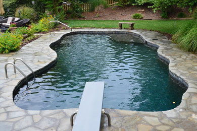 На фото: большой бассейн произвольной формы на заднем дворе в классическом стиле с покрытием из каменной брусчатки