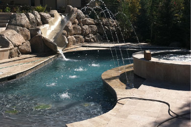 Immagine di una piccola piscina naturale tradizionale personalizzata dietro casa con una vasca idromassaggio e pavimentazioni in pietra naturale