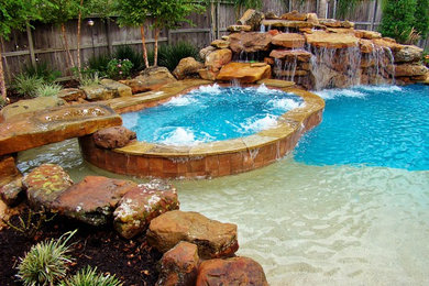 Design ideas for a large modern back custom shaped swimming pool in Houston with a water feature and stamped concrete.