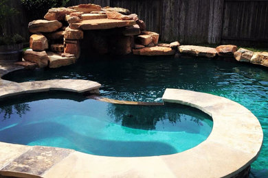 Modelo de piscinas y jacuzzis alargados de estilo americano de tamaño medio tipo riñón en patio trasero con adoquines de piedra natural