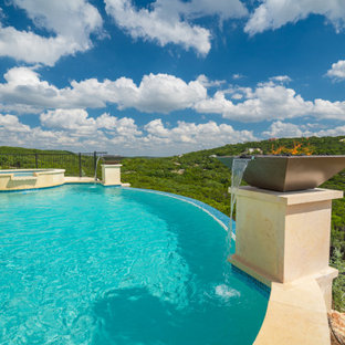 Esempio di una grande piscina a sfioro infinito design personalizzata dietro casa con pedane