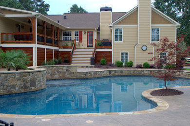 Example of a large classic backyard stamped concrete and custom-shaped pool house design in Atlanta