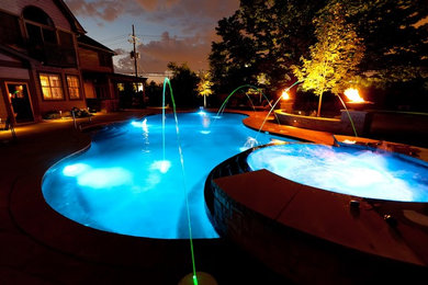 Ejemplo de piscina con fuente natural tradicional renovada de tamaño medio a medida en patio trasero con adoquines de piedra natural