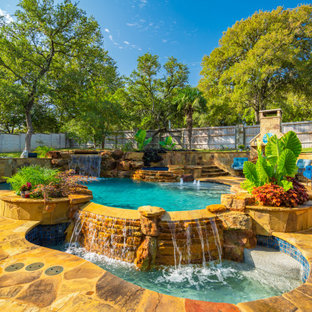 Ispirazione per una grande piscina naturale tropicale personalizzata dietro casa con pedane