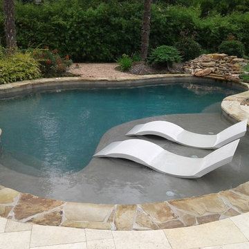 Freeform pool with tanning ledge, ledge loungers, rock waterfall, cocktail table